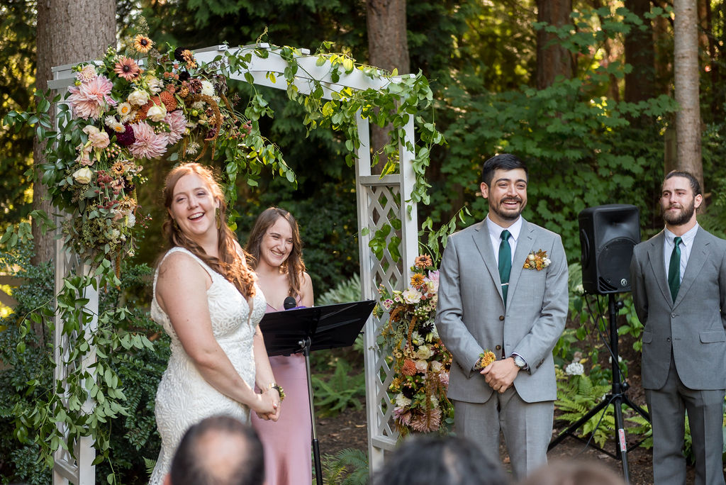 Bainbridge-Island-Wedding-Floral-Arch-Vows Bride and groom saying their vows in front of a floral arch