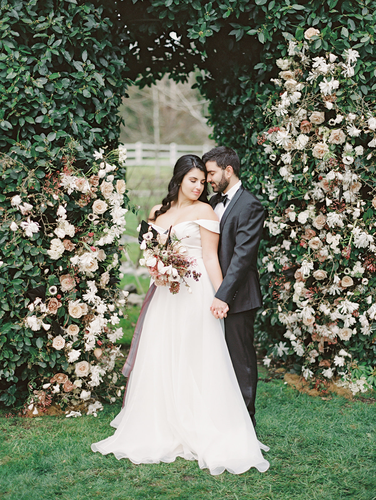 Chateau-Lill-Wedding-Bride-and-Groom-Floral-Arch.jpg A bride and groom embracing in front of a floral arch installation in the garden hedge at Chateau Lill