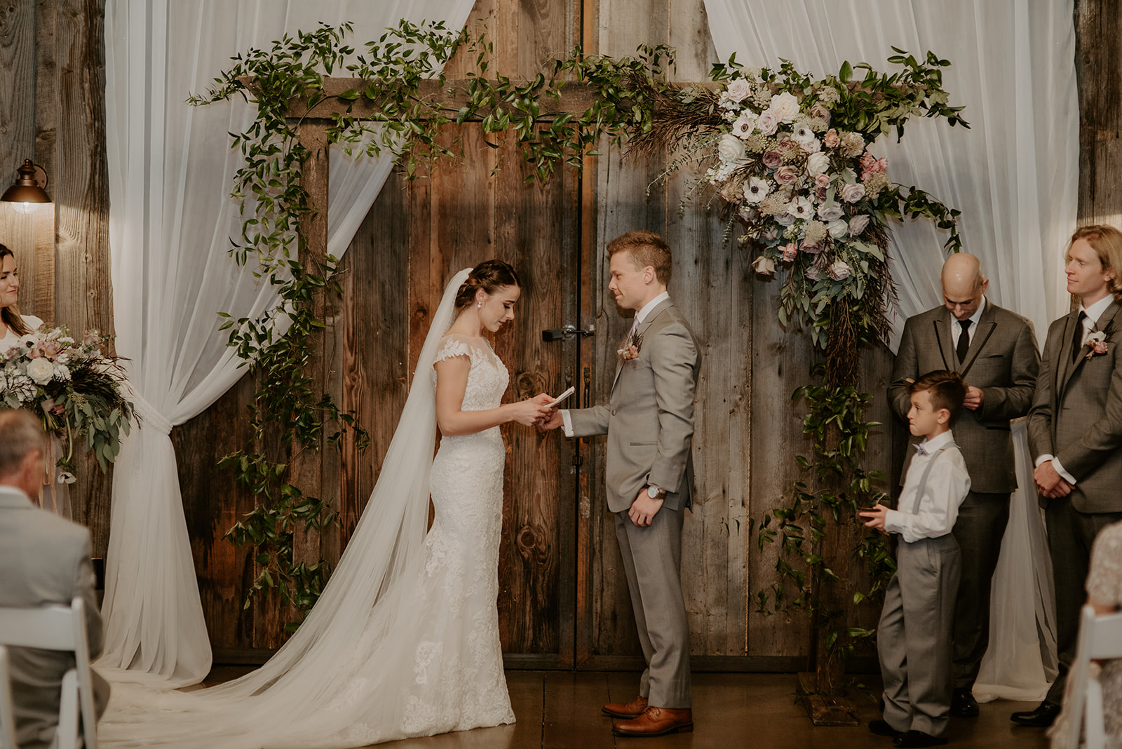Kelley-Farm-Wedding-Saying-Vows.jpg Bride and groom saying vows in front of floral arch