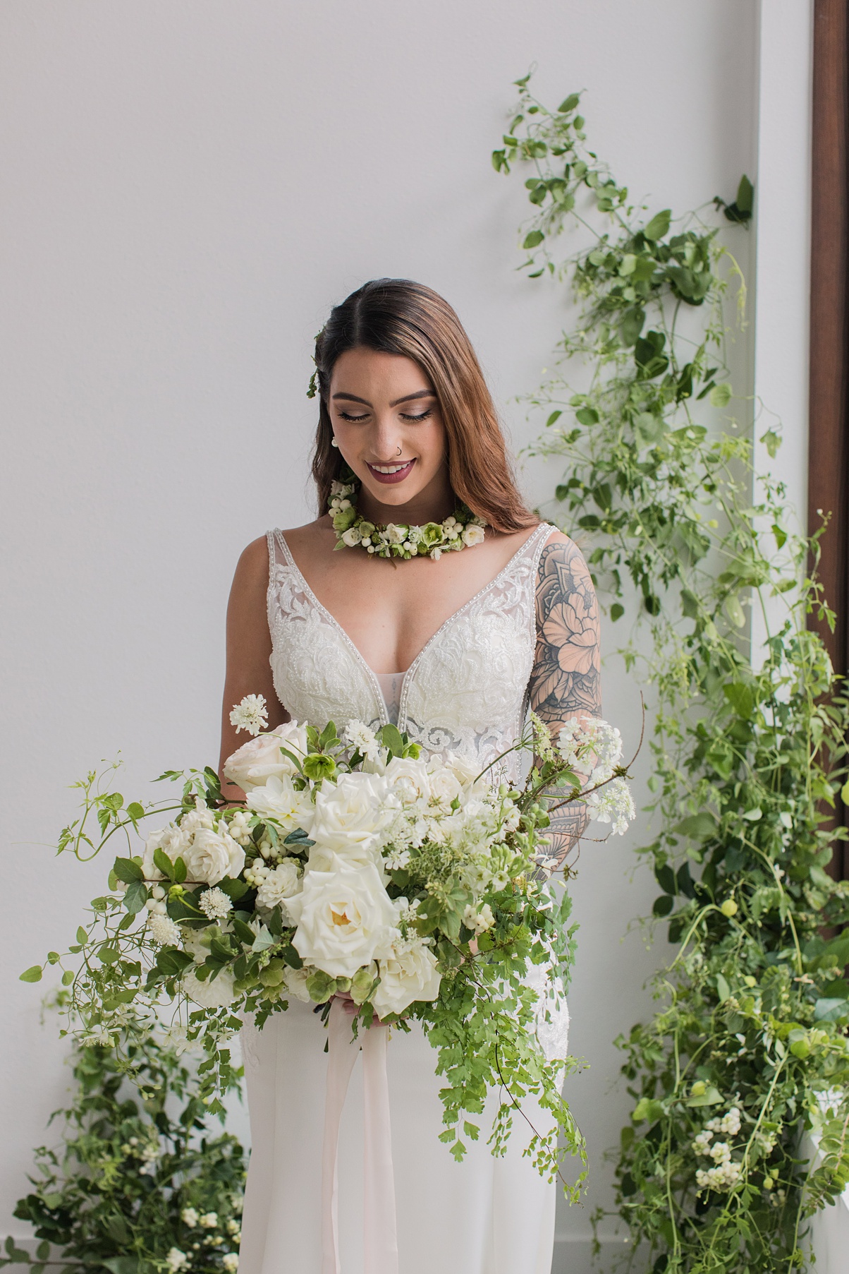A bride holding a white bouquet in front of a floral installation