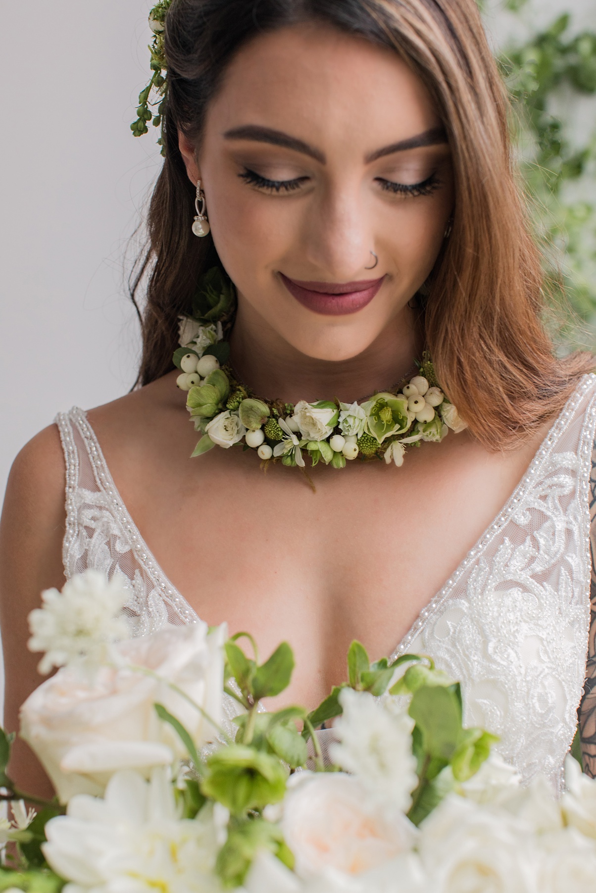 A bride holding a bouquet and wearing a floral necklace