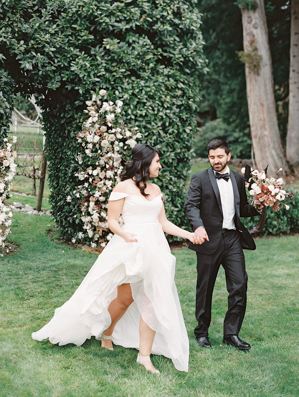 a couple walking across the grounds of Chateau Lill with a floral installation in the background