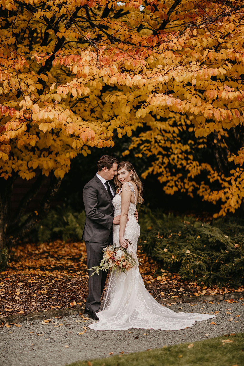 Folk Art Flowers Best Outdoor Wedding Venues in Seattle_0002 a bride and groom standing under a tree with bright yellow fall leaves