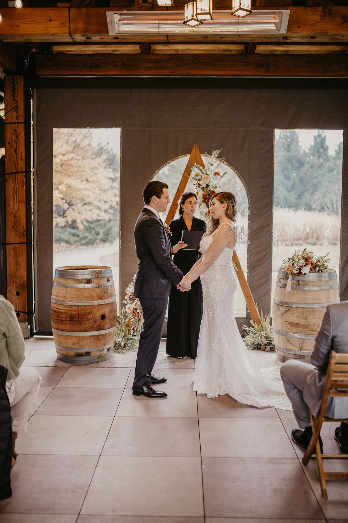 Willows-Lodge-Wedding-Ceremony-Garden-Gazebo-Tented the couple holding hands in front of their ceremony florals in the tented gazebo