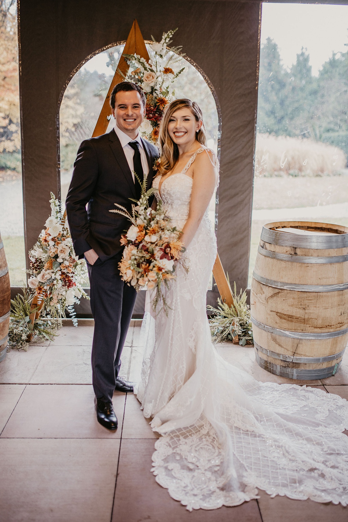 Willows-Lodge-Wedding-Couple-Holding-Bridal-Bouquet the bride and groom standing in front of their floral arch, with the bride holding her bouquet