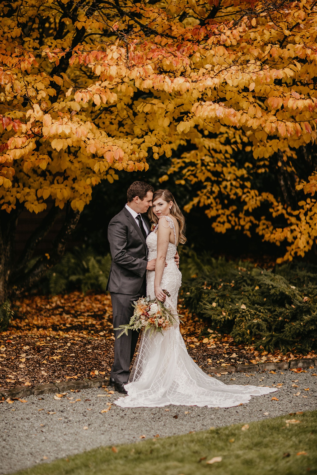 Willows-Lodge-Wedding-Fall-Foliage-in-Gardens a bride and groom stand under fall foliage at the Willows Lodge