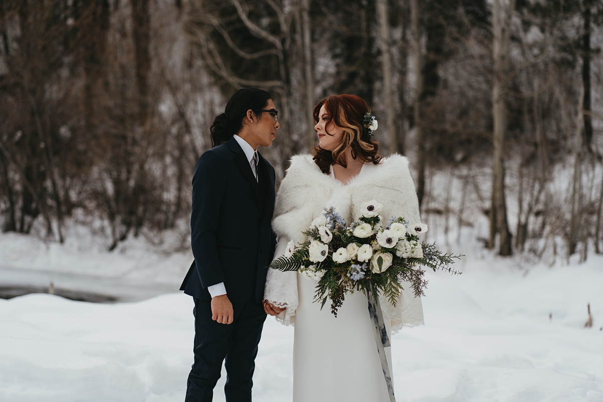a couple holding each other, the bride with her bouquet wearing white furs