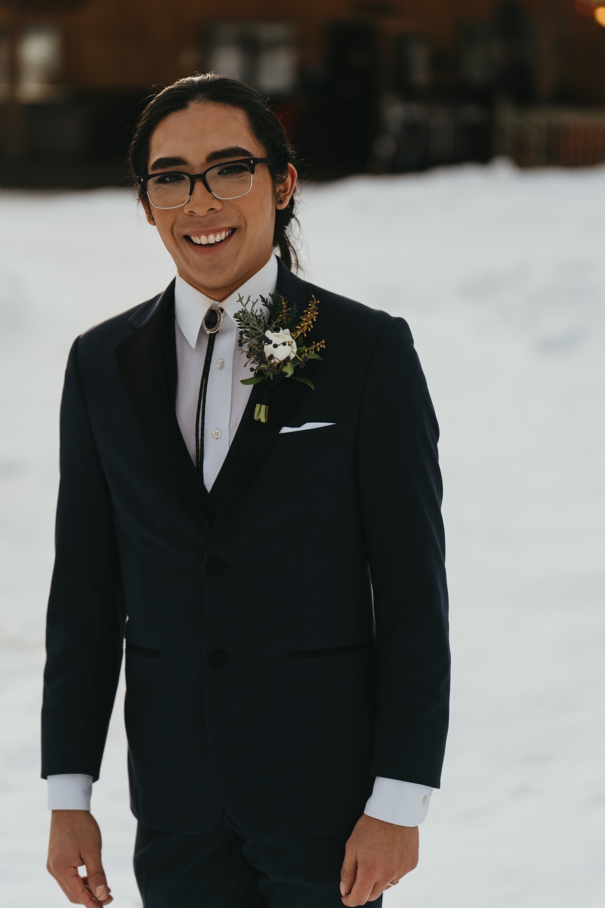 Evan with a boutonniere, smiling in the snow
