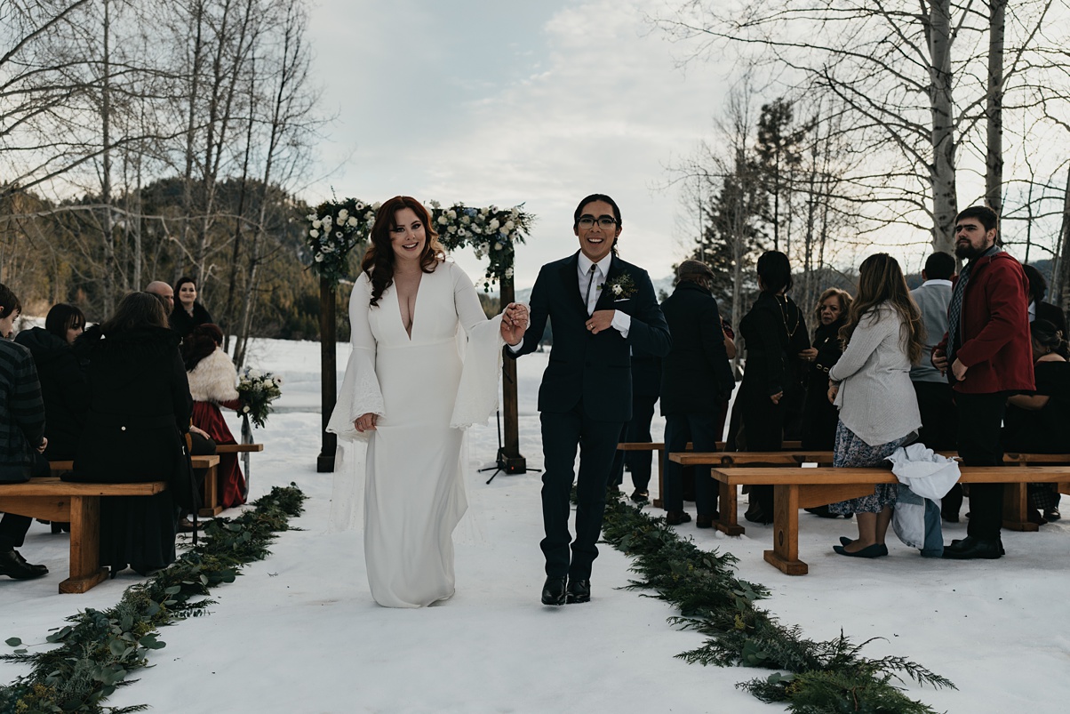 The couple, just married, walking down the aisle smiling
