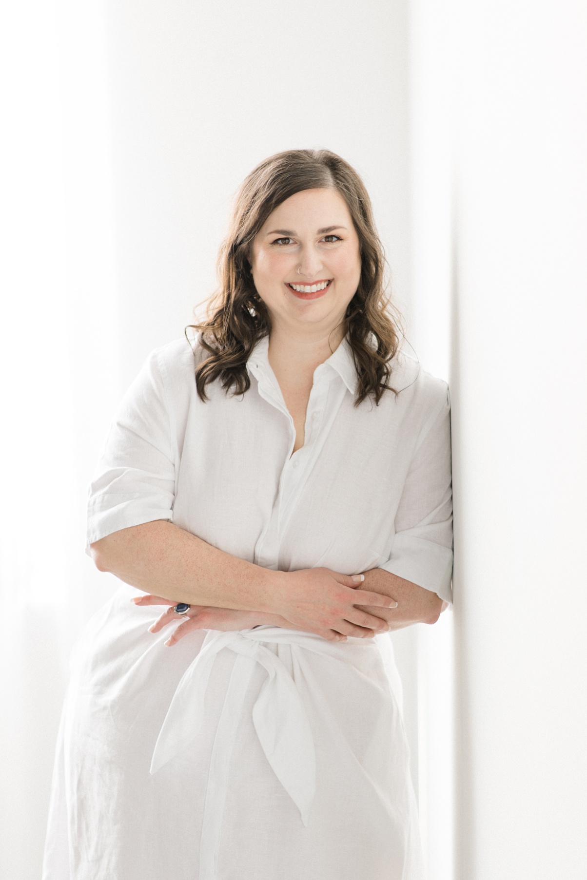 Seattle Wedding Florist Carolyn Kulb, Carolyn Kulb, owner of Bloom Poet, Seattle Wedding Florist, leaning on a white wall