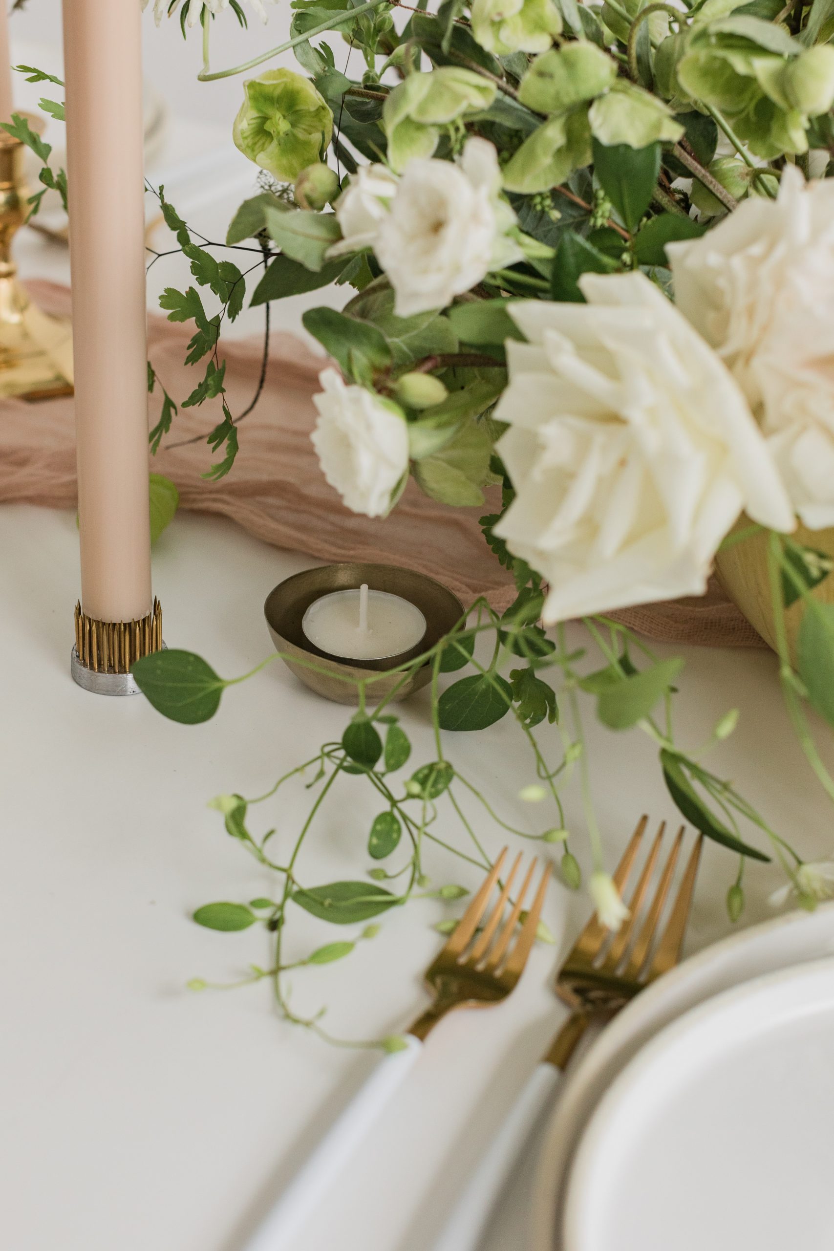 A white wedding table setting with taper and votive candles