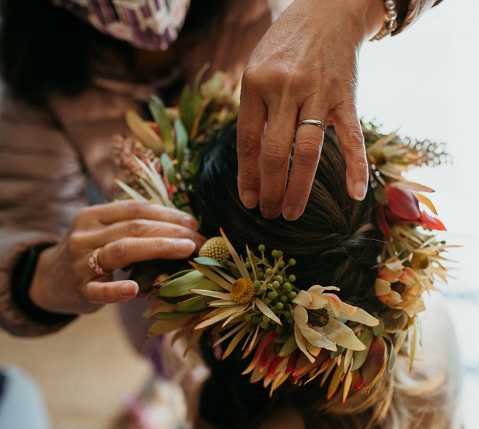 Mom pins a tropical wedding flower crown on the bride