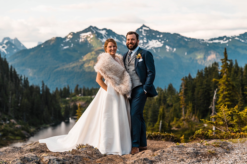 Mountain-Wedding-with-Vibrant-Summer-Blooms-Couple-with-Mountains A couple stands on a mountaintop after their wedding