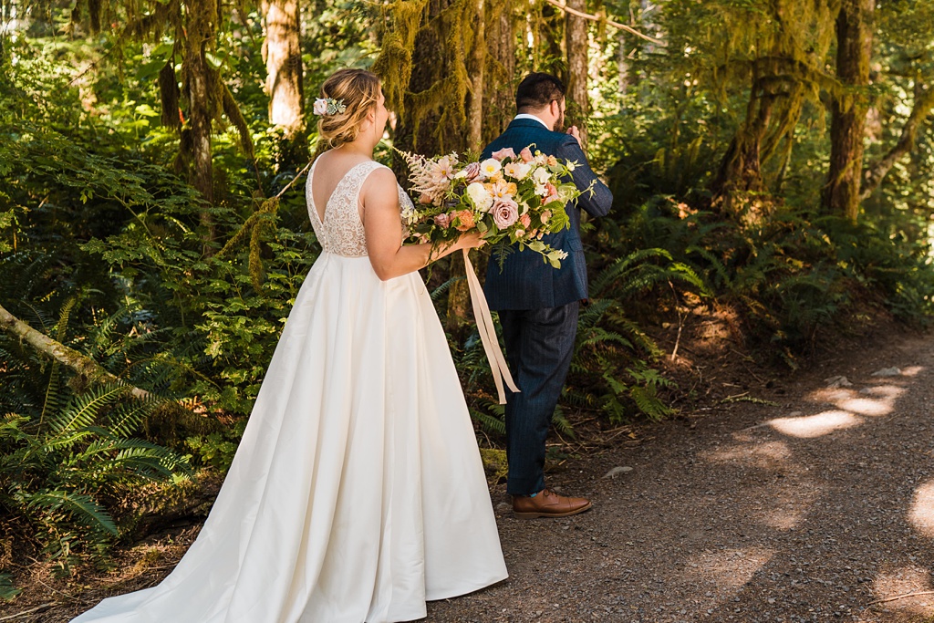 Mountain-Wedding-with-Vibrant-Summer-Blooms-First-Look-Holding-Bouquet The bride approaches the groom for the first look