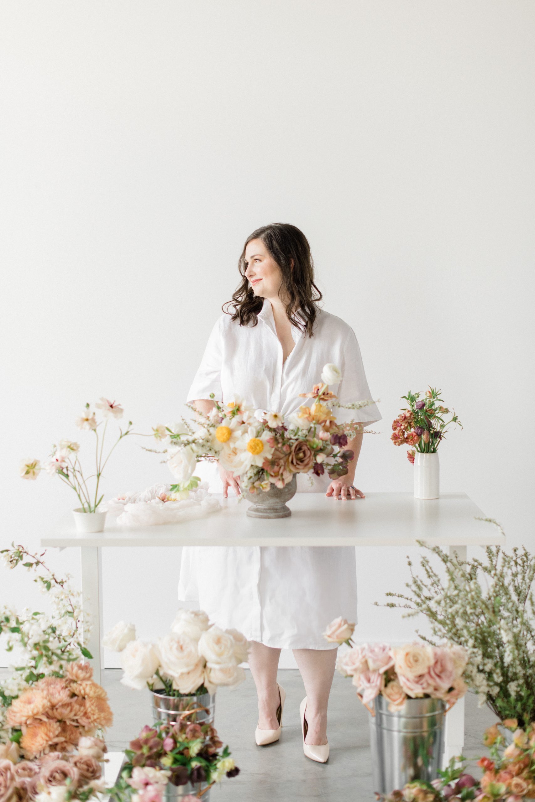 Bloom-Poet-Seattle-Wedding-Florist-Work-With-Us-Carolyn-with-Flower-Studio Owner Carolyn Kulb standing in a flower studio, surrounded by flowers