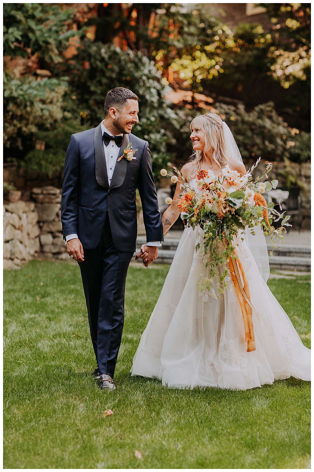 Seattle-Wedding-Florist-Bloom-Poet-Fall-Wedding-Boho-Flowers--Couple-Walking-on-Lawn The bride and groom walk across the lawn, holding the bouquet