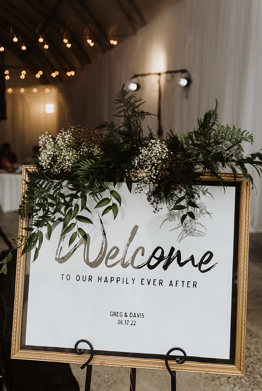 A wedding welcome sign designed with foliage and light florals
