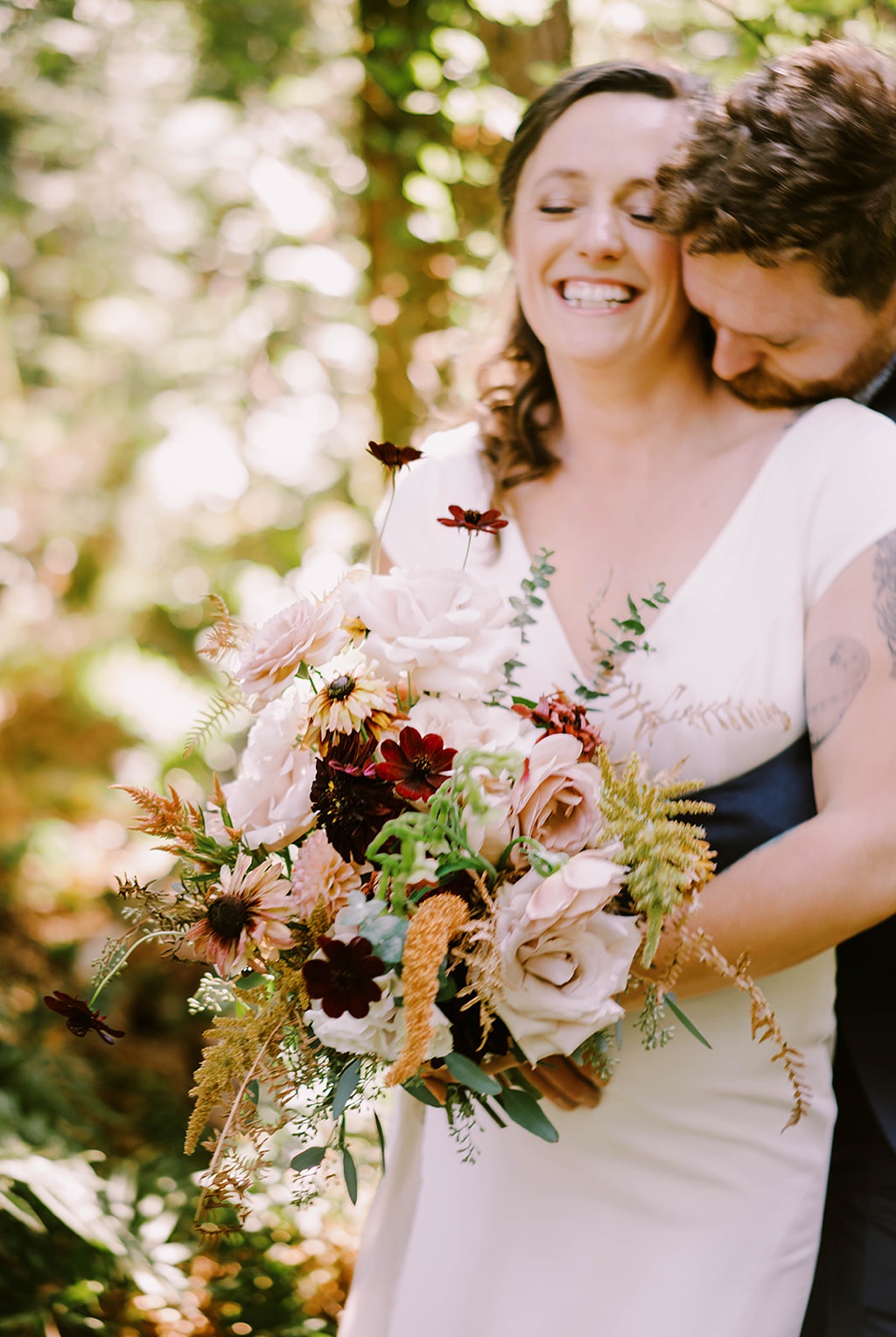 Bloom-Poet-Seattle-Wedding-Florist-Summer-Wedding-Couple-Holding-Bouquet.jpg A couple laughing and holding a bouquet in this summer wedding